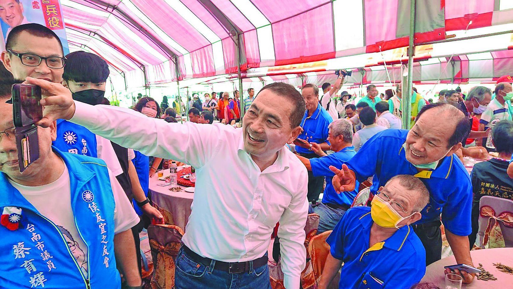 台南市新營太子宮28日中午舉辦平安宴,國民黨總統參選人侯友宜(中)走入餐席,大方與民眾自拍合影。(程炳璋攝) image