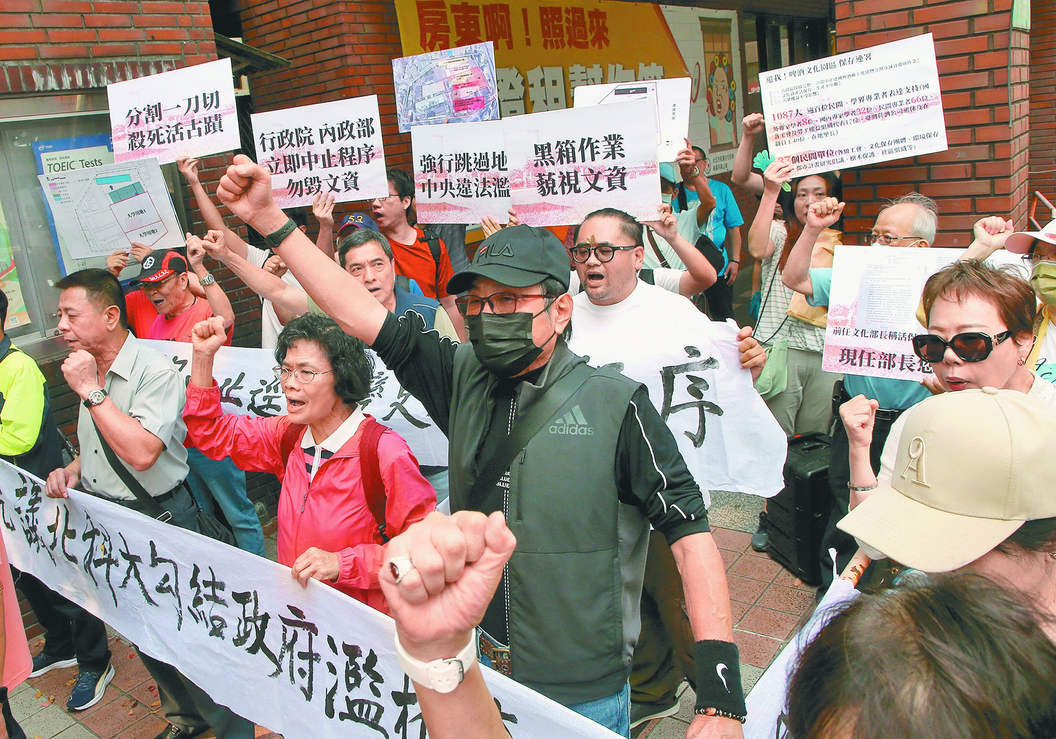 內政部國土管理署16日審議建國啤酒廠都市計畫案,傳出部分用地,未來得割讓給台北科技大學,作為蓋新校舍使用,引發文資團體不滿到會場外抗議,手拿標語旗幟表達不滿。(趙雙傑攝) image