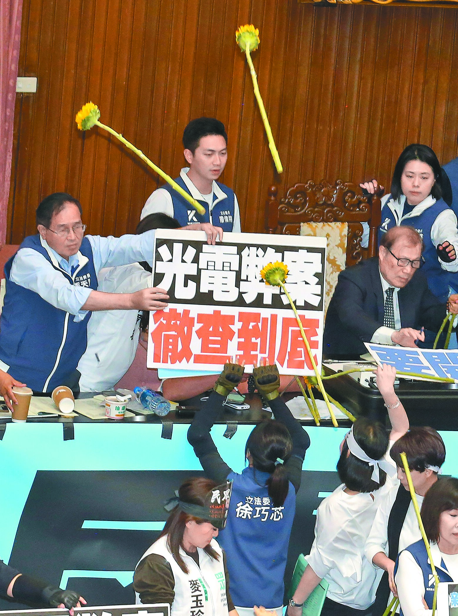 立法院院會21日續審國會改革法案,民進黨立委人手一支向日葵高唱〈島嶼天光〉,並憤而將花砸向立委黃國昌,一旁的立委鄭天財(左)見狀用標語擋住。(范揚光攝) image