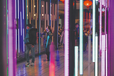 電費是否再調漲?由於立法院還未同意撥補,將對台電財務有很大的影響,如果最後沒有撥補,台電就必須舉債。圖為民眾經過裝滿霓虹燈的天橋。(羅永銘攝) image