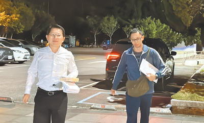 花蓮縣政府民政處長明良臻(左)25日晚間9時45分許,被移送花蓮地檢署複訊,手拿還未開封的便當。(羅亦晽攝) image