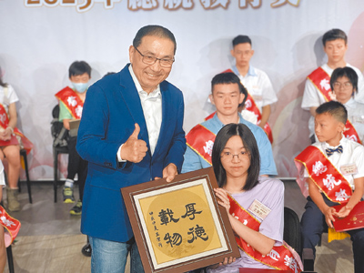 新北市碧華國中學生王潔沂(前排右)因罹患脊髓性肌萎縮症,從小經歷病痛考驗,21日在新北市教育局表揚榮獲總統教育獎的頒獎典禮上,帶來親筆手寫的「厚德載物」書法作品送給市長侯友宜(前排左)。(柯毓庭攝) image