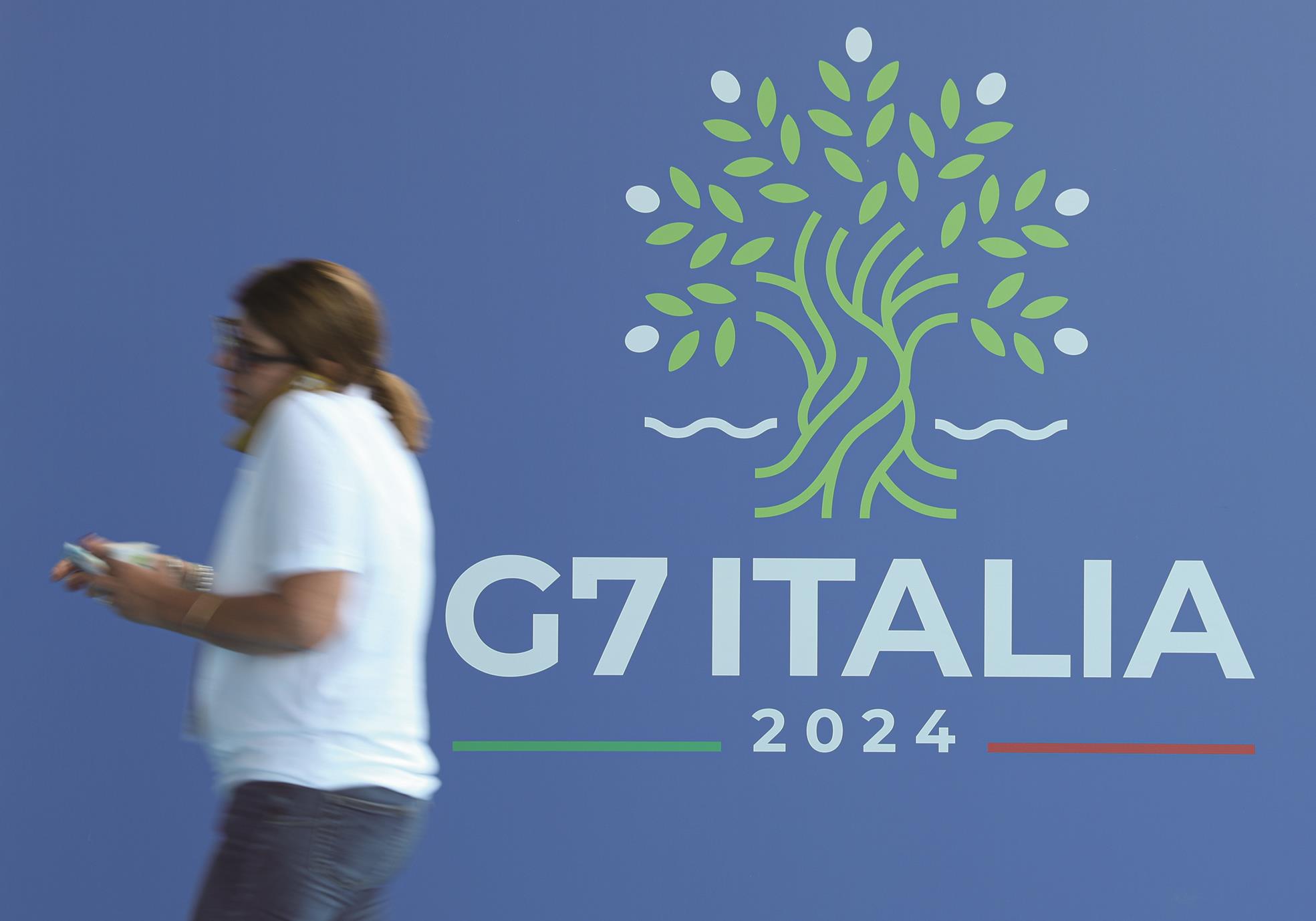 一名女子經過G7峰會的展板。圖為2024年在義大利召開的G7峰會。(新華社) image