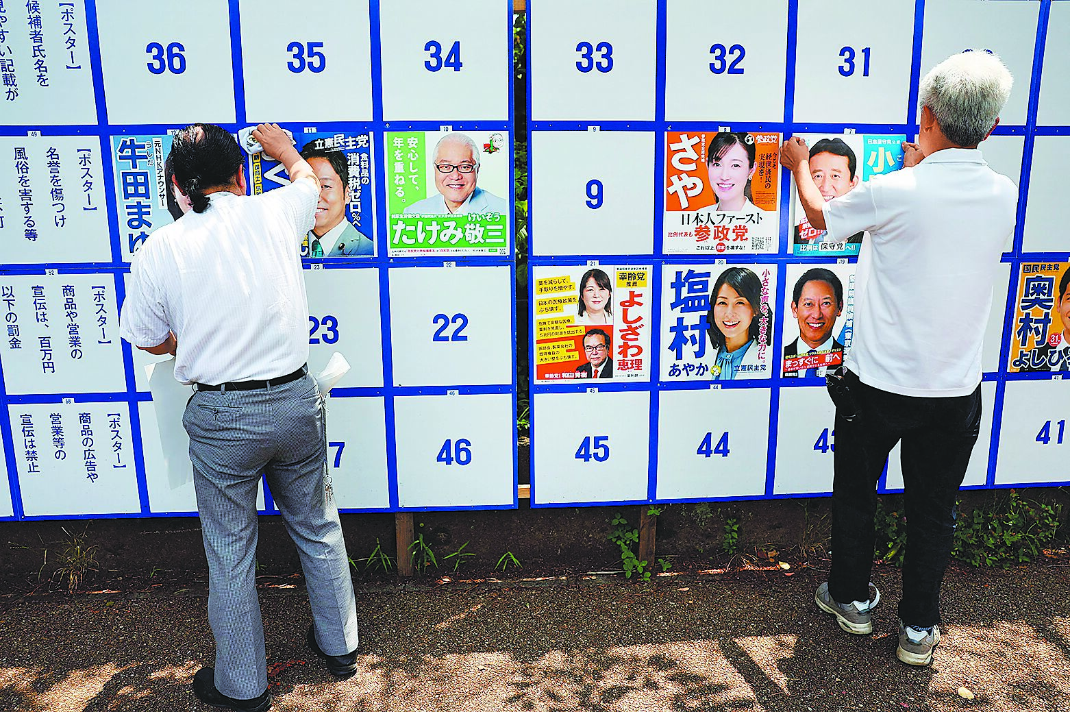 日本20日將舉行參議院選舉,候選人的支持者在公告欄上張貼競選海報。(路透) image