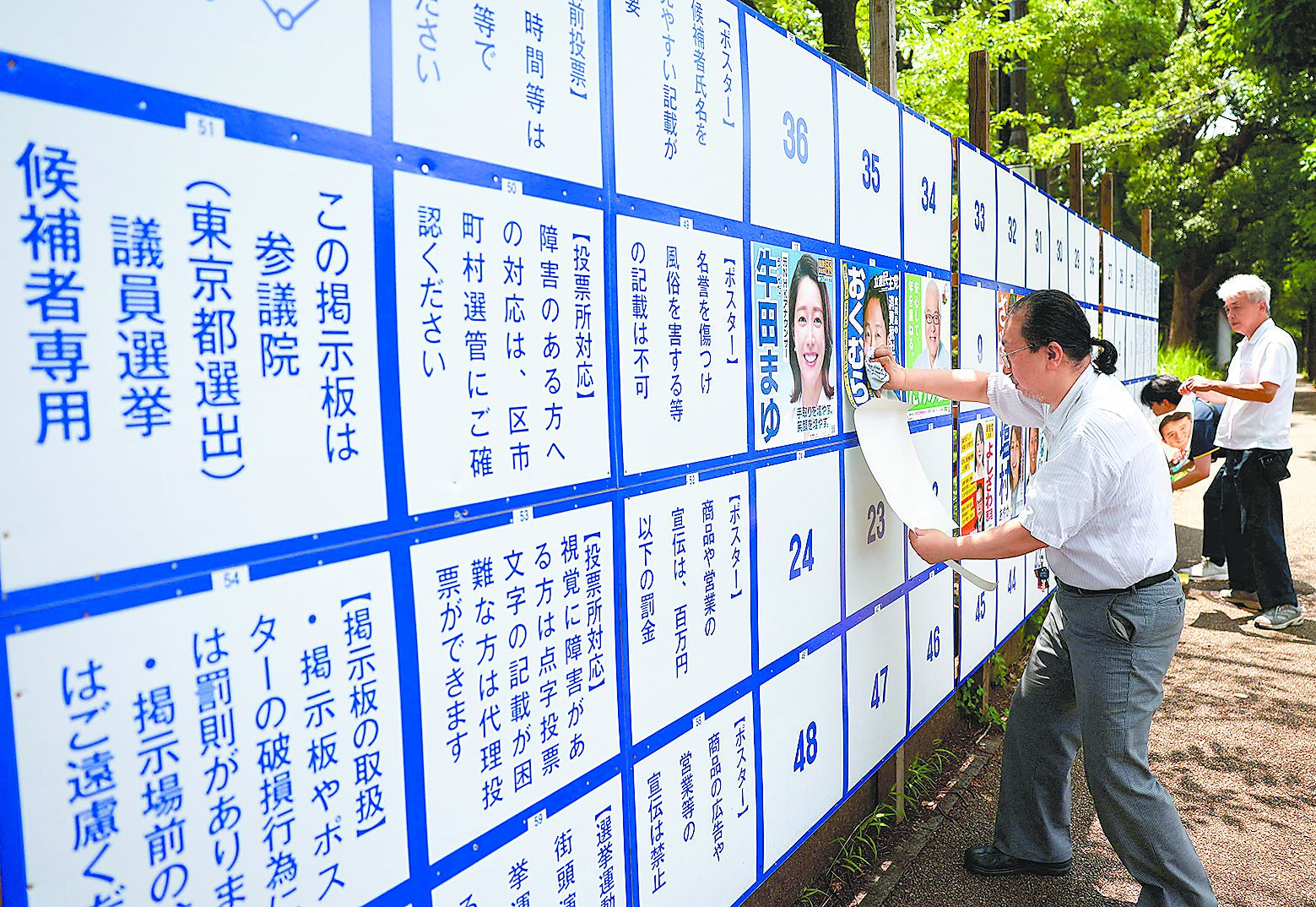 日本參議院選舉將至,支持者在東京街頭公告欄上張貼候選人競選海報。(路透) image