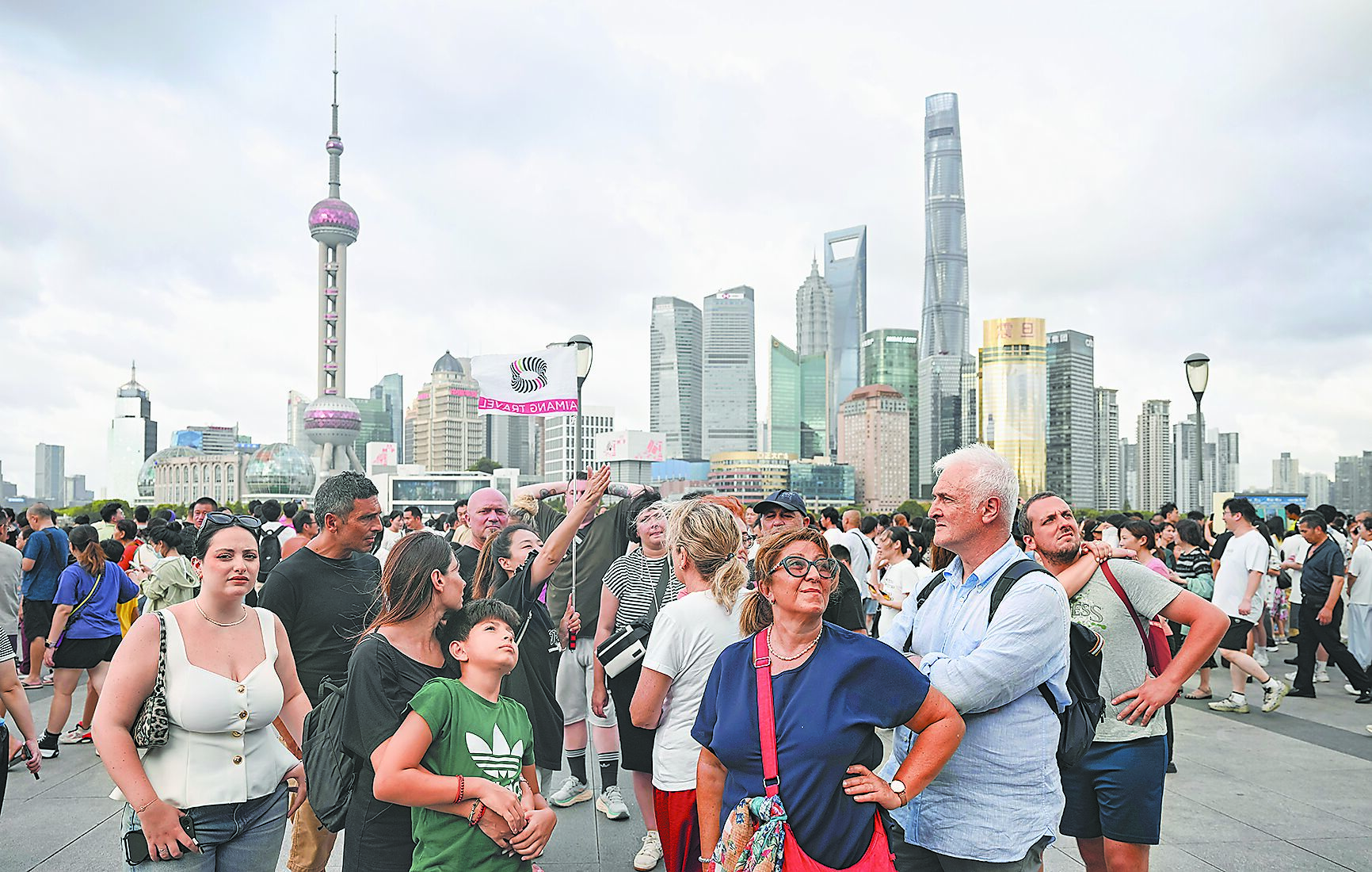 中國大陸已對75國實行單方面免簽或全面互免簽證,簽證便利化政策措施有效帶動大批外國遊客赴中國旅遊。圖為義大利遊客在上海外灘聽導遊介紹景點。(新華社) image