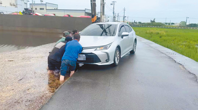 有民眾開車行經彰化縣伸港鄉曾家村一處道路,右前輪陷進水田中,附近工廠老闆與5名越南籍移工見狀,合力協助車子脫困。(賴清美提供/葉靜美彰化傳真) image