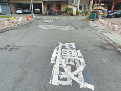 國民黨高市議員李雅靜近日在鳳山區會勘時,發現和興街路面不僅嚴重破損,且出現「慢」字顛倒還重疊畫設的「交通奇觀」。(洪浩軒攝) image